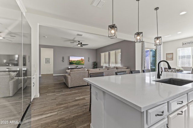 kitchen with a ceiling fan, visible vents, dark wood-style flooring, a sink, and open floor plan