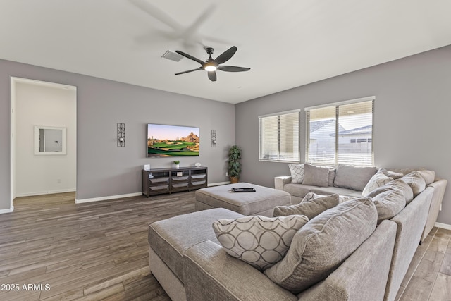 living room featuring a ceiling fan, visible vents, wood finished floors, and baseboards