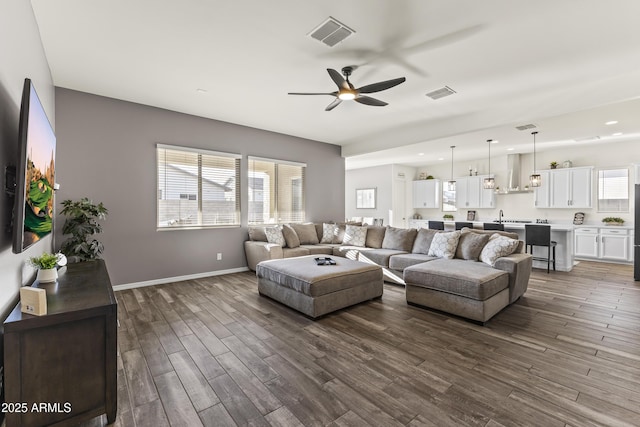 living area with a ceiling fan, baseboards, visible vents, and dark wood-style flooring