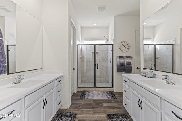 bathroom featuring visible vents, a stall shower, wood finished floors, and a sink