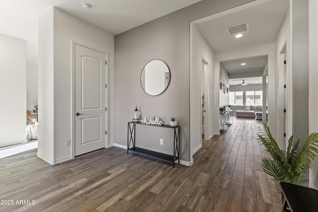 hallway with recessed lighting, wood finished floors, visible vents, and baseboards