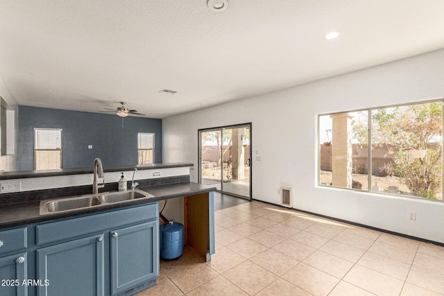 kitchen with visible vents, blue cabinetry, light tile patterned flooring, a sink, and dark countertops