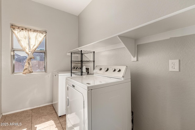 clothes washing area with light tile patterned floors, baseboards, separate washer and dryer, and laundry area