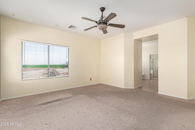 carpeted empty room with visible vents, baseboards, and ceiling fan