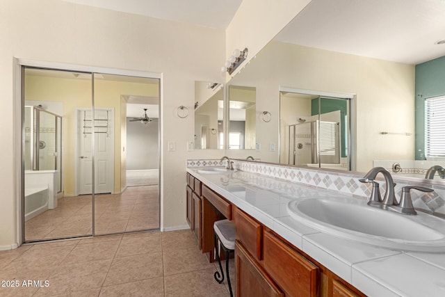 bathroom featuring tile patterned floors, double vanity, a stall shower, and a sink