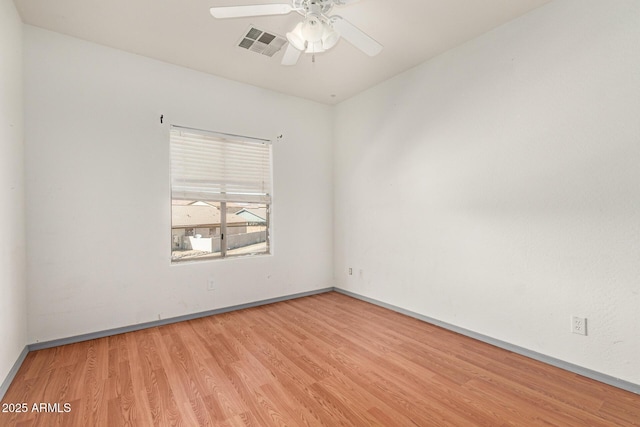 empty room with baseboards, wood finished floors, visible vents, and ceiling fan