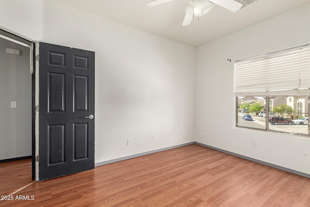 empty room with baseboards, wood finished floors, and a ceiling fan