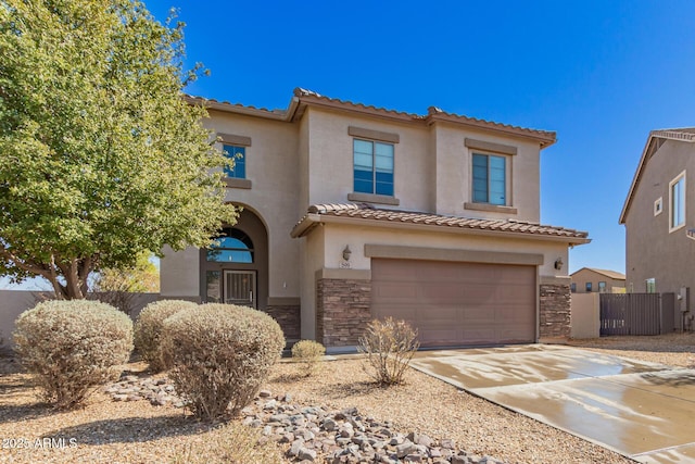 mediterranean / spanish home featuring stucco siding, stone siding, an attached garage, and a tiled roof