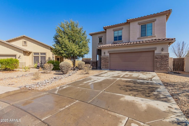 mediterranean / spanish house with driveway, an attached garage, stucco siding, stone siding, and a tile roof