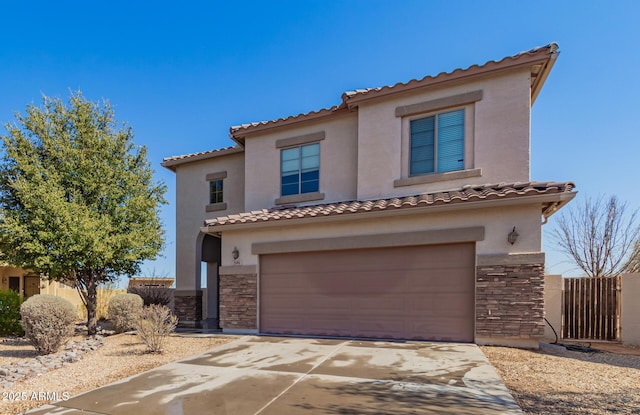 mediterranean / spanish home with a tile roof, an attached garage, stone siding, and stucco siding