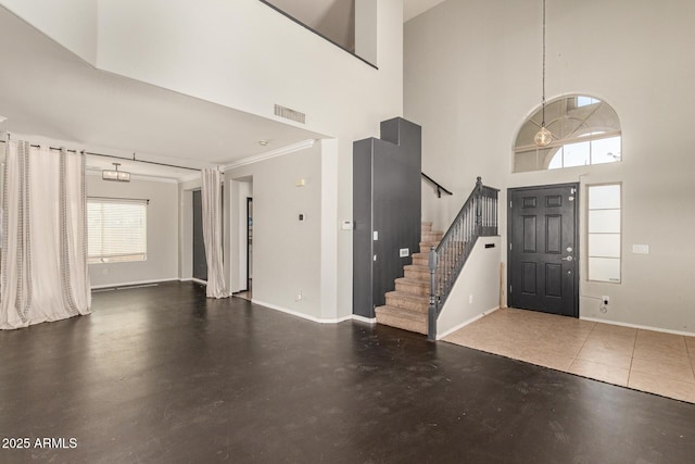 foyer featuring visible vents, concrete floors, baseboards, stairs, and a towering ceiling