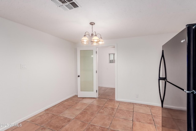 tiled spare room featuring a chandelier