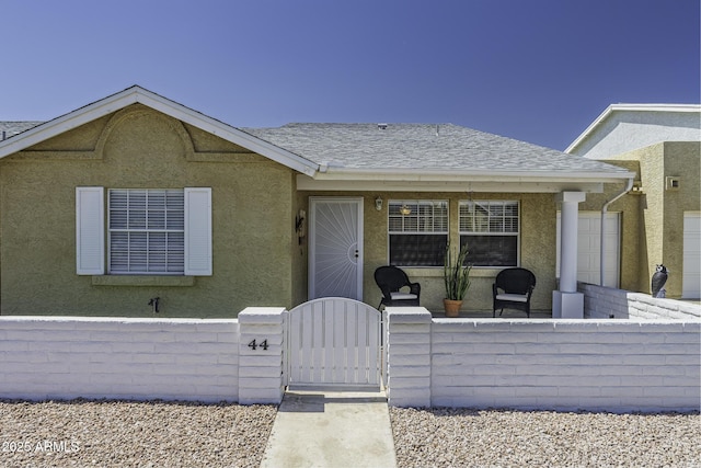 2929 E Broadway Rd Unit 44, Mesa, AZ 85204 - view of front of home with a fenced front yard, a gate, stucco siding, and roof with shingles