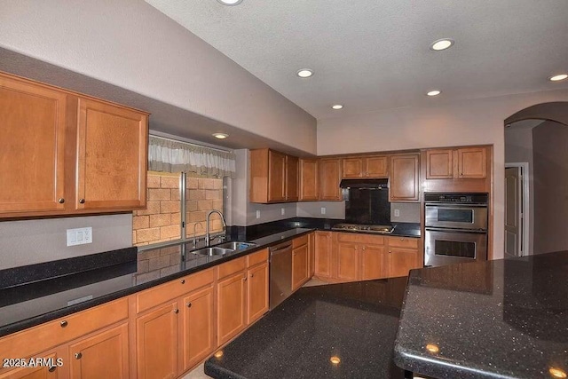 kitchen featuring stainless steel appliances, dark stone countertops, and sink