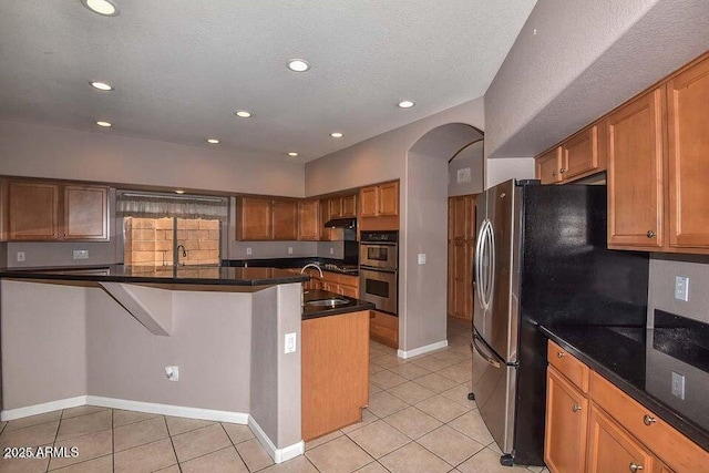 kitchen with a textured ceiling, stainless steel appliances, sink, kitchen peninsula, and light tile patterned floors