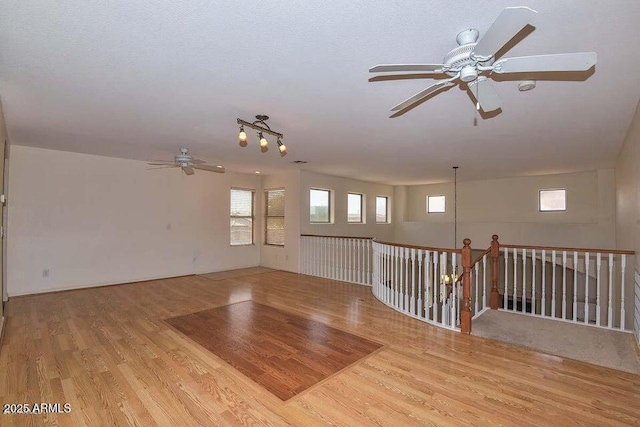 empty room with light wood-type flooring, ceiling fan, and a textured ceiling