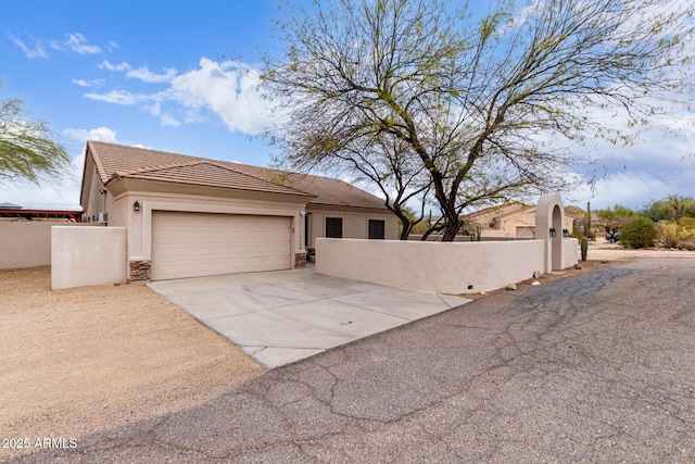 view of front of home with concrete driveway, a fenced front yard, a tiled roof, an attached garage, and stucco siding