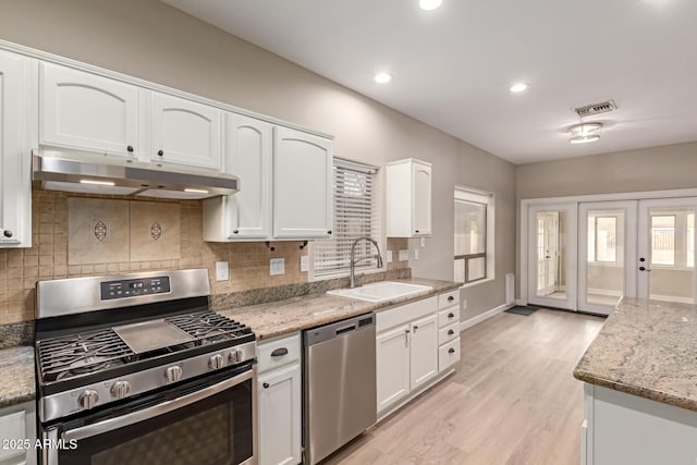 kitchen featuring under cabinet range hood, a sink, white cabinetry, visible vents, and appliances with stainless steel finishes