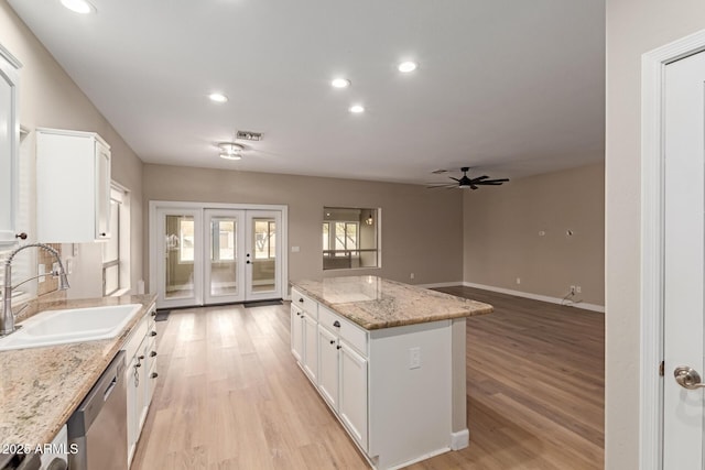 kitchen with a sink, visible vents, light wood-style floors, white cabinetry, and dishwasher