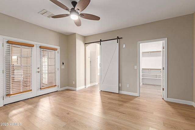 interior space with access to exterior, french doors, light wood finished floors, and a barn door