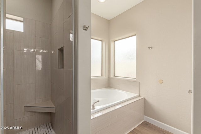 bathroom with baseboards, a bath, and tiled shower