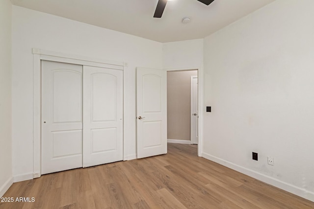 unfurnished bedroom with light wood-style floors, a closet, ceiling fan, and baseboards