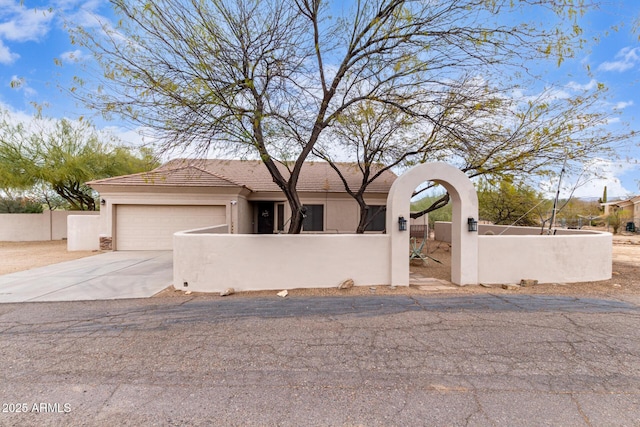 view of front of property featuring an attached garage, a fenced front yard, concrete driveway, and stucco siding