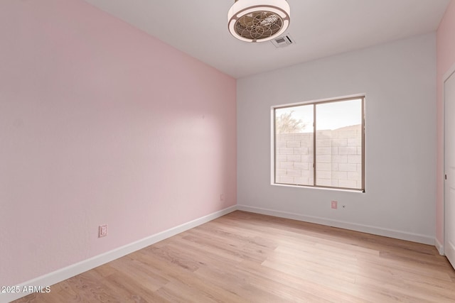 empty room featuring light wood-style floors, baseboards, and visible vents