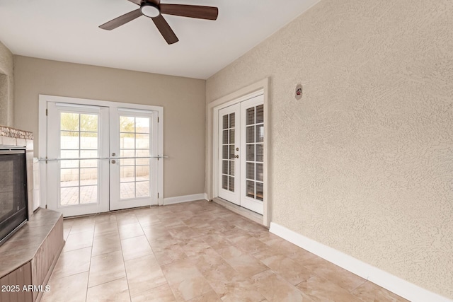 doorway featuring french doors, a textured wall, baseboards, and ceiling fan