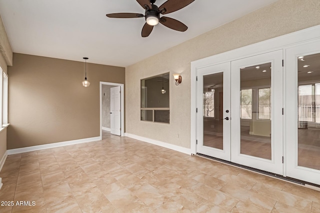 spare room with a ceiling fan, french doors, and baseboards