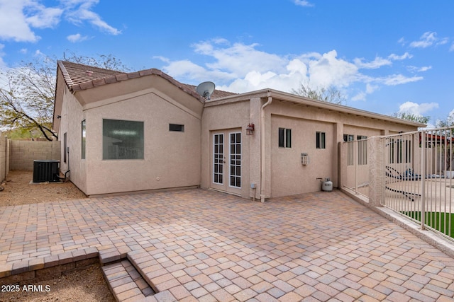 rear view of house with central air condition unit, a patio area, fence, and stucco siding