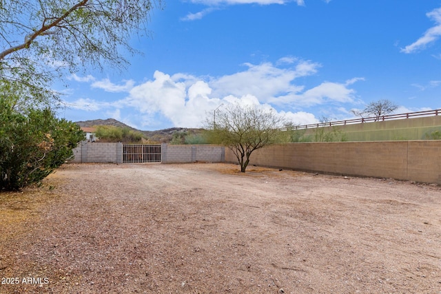 view of yard featuring a mountain view, fence, and a gate