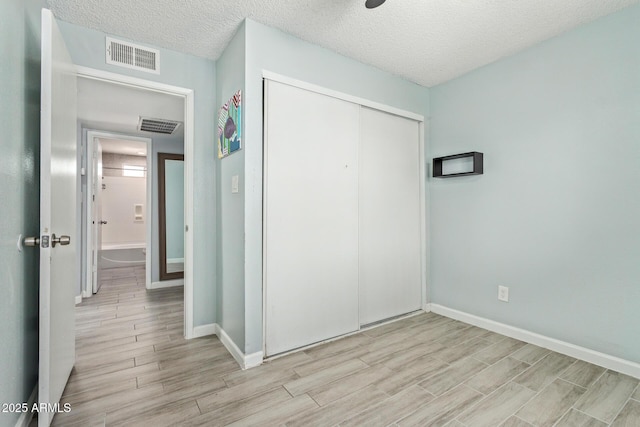 8051 W Mariposa Dr, Phoenix, AZ 85033 - unfurnished bedroom with light wood-style floors, baseboards, a closet, and a textured ceiling
