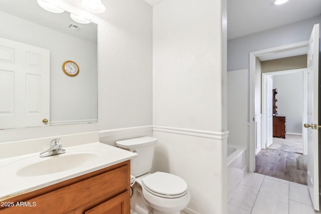 bathroom featuring toilet, vanity, tile patterned flooring, and a bath