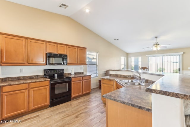 kitchen with sink, ceiling fan, light hardwood / wood-style flooring, black appliances, and a kitchen island with sink