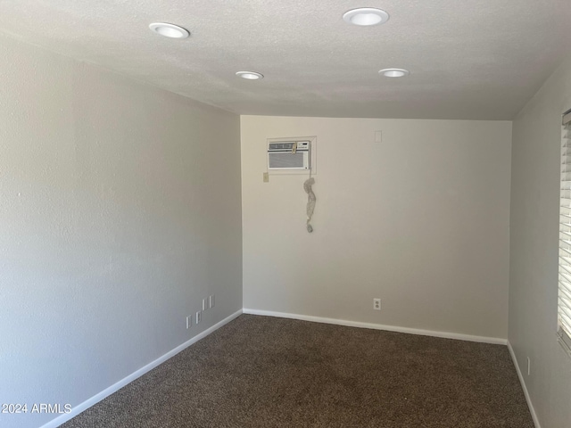 unfurnished room featuring a wall unit AC, a textured ceiling, and carpet