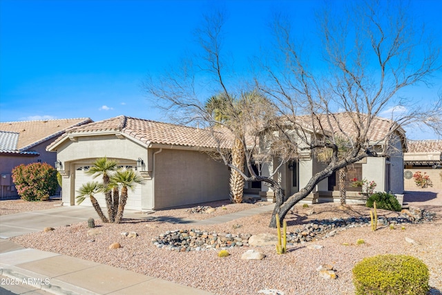 view of front of house with a garage, a tiled roof, concrete driveway, and stucco siding