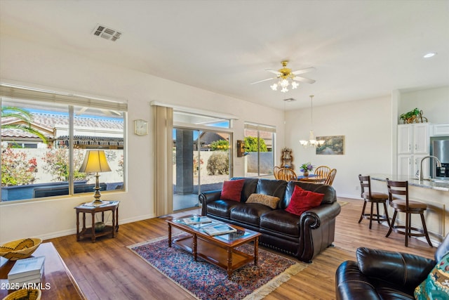 living room featuring sink, ceiling fan with notable chandelier, and wood-type flooring