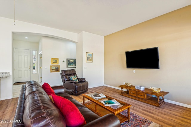 living area featuring arched walkways, baseboards, and wood finished floors