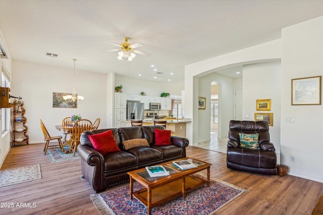 living room with ceiling fan with notable chandelier and light wood-type flooring