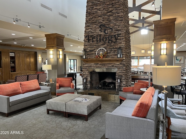 living area with a towering ceiling, visible vents, a wealth of natural light, and a stone fireplace