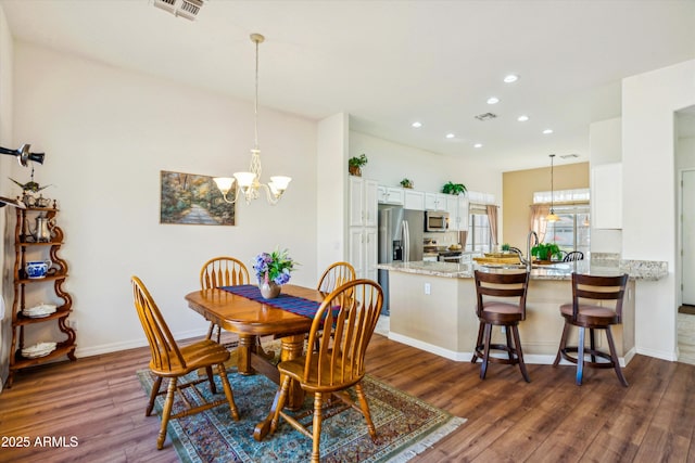 dining area featuring visible vents, a notable chandelier, and wood finished floors