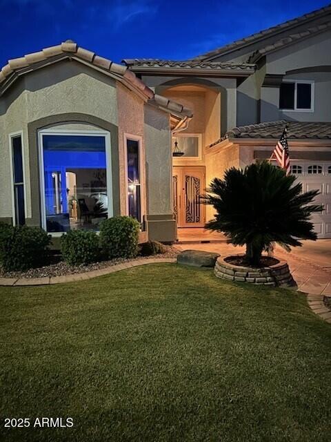 1292 N Renee Ave, Gilbert, AZ 85234 - view of exterior entry featuring a tile roof, stucco siding, and a yard