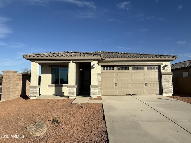 prairie-style house with driveway, stone siding, a tiled roof, an attached garage, and stucco siding