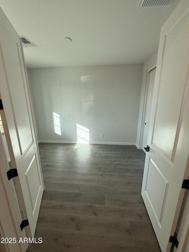 interior space with baseboards, visible vents, and dark wood finished floors