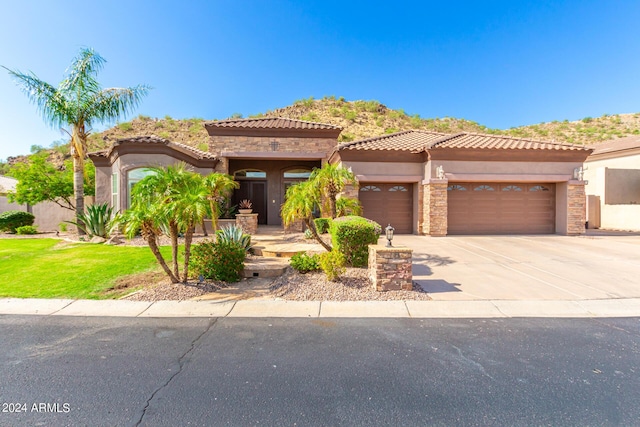 9845 E Inglewood St, Mesa, AZ 85207 - mediterranean / spanish-style home with concrete driveway, stone siding, a tile roof, an attached garage, and stucco siding