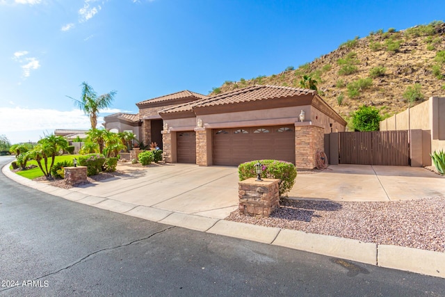 mediterranean / spanish-style home featuring an attached garage, a tile roof, stone siding, driveway, and stucco siding