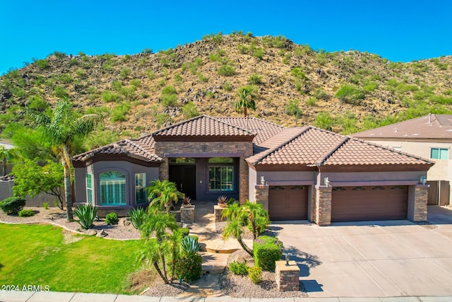 9845 E Inglewood St, Mesa, AZ 85207 - mediterranean / spanish-style home featuring a garage, stone siding, a tiled roof, and stucco siding