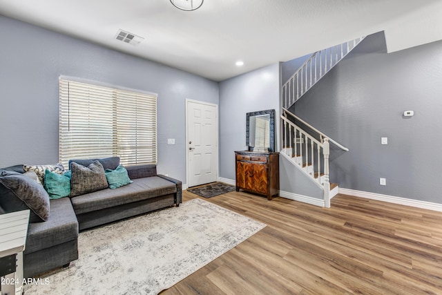 living room featuring wood finished floors, visible vents, baseboards, and stairs