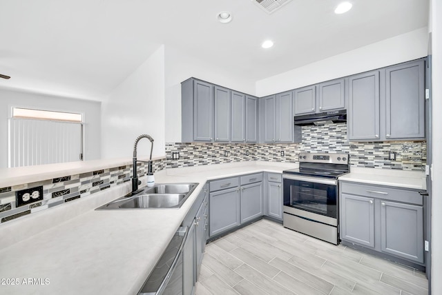 7207 W Alta Vista Rd, Laveen, AZ 85339 - kitchen with stainless steel electric range oven, under cabinet range hood, gray cabinetry, backsplash, and light countertops